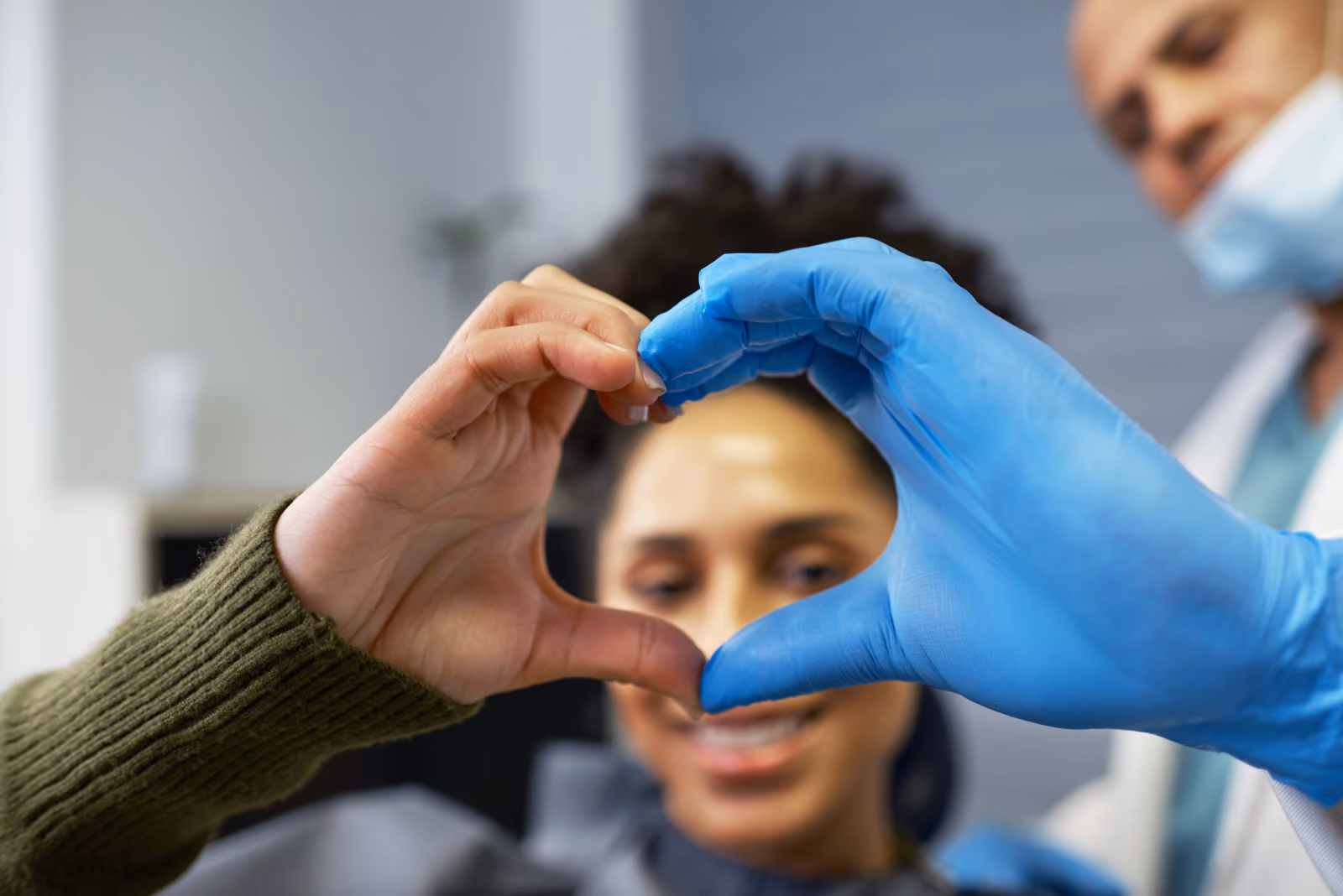 Patient and dentist making a heart shape with their hands